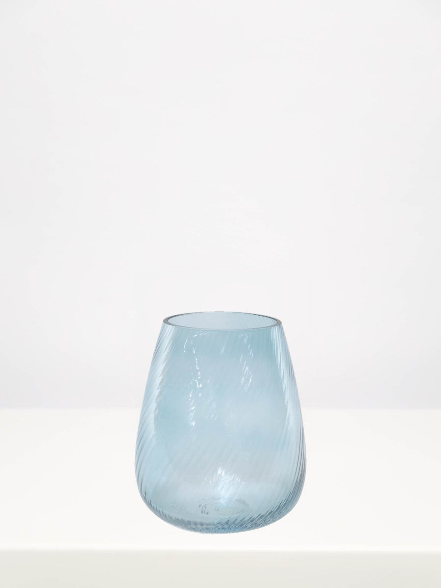 Soft Blue Ribbed Vase - 18cm on a white table against a soft grey wall
