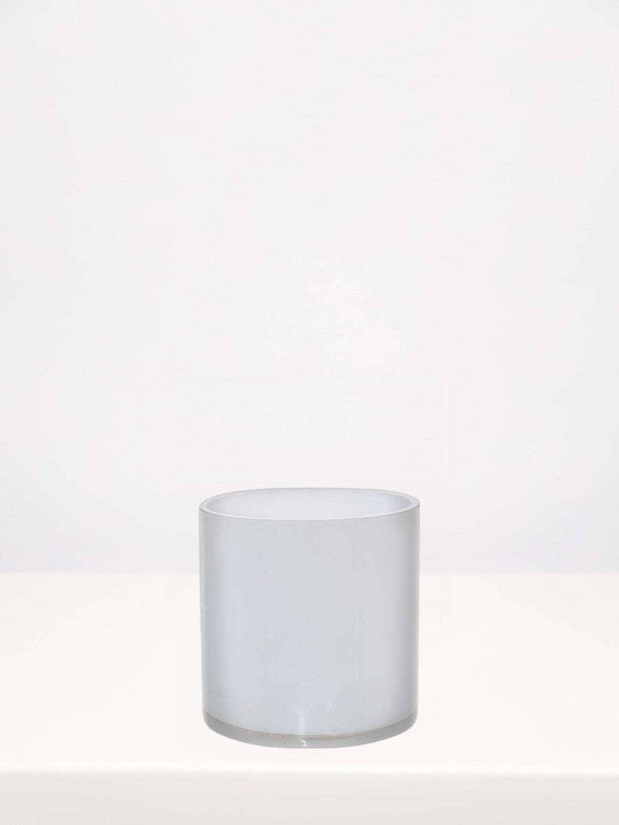 White Round Cylinder Vase - 15cm on a white table against a soft grey wall